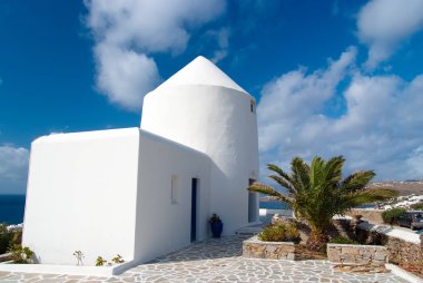 Badanalı bina ve palmiye Mykonos, Yunanistan. Deniz güneşli mavi gökyüzü üzerinde eve. Tipik ev mimarisi ve tasarım. Bir Akdeniz Adası yaz tatili. Yolculuk tutkusu ve seyahat kavramı