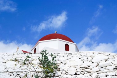 Taş çit ve ayrıntı Mykonos, Yunanistan için çapraz kırmızı kubbe. Güneşli açık mimarisi bina Kilisesi. Mavi gökyüzü Şapel. Din ve kült kavramı. Bir Akdeniz Adası yaz tatili