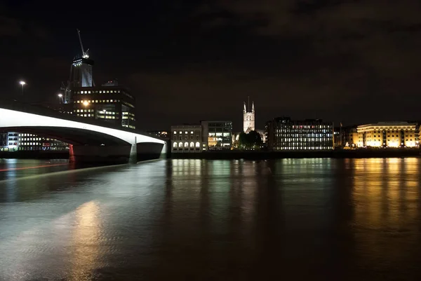 Skyline uitzicht vanaf de rivier op de donkere hemel in Londen, Verenigd Koninkrijk. Stad en brug met nacht verlichting. Gebouwen reflectie op het water met mooie architectuur. Structuur en ontwerp. Reizen en reis — Stockfoto