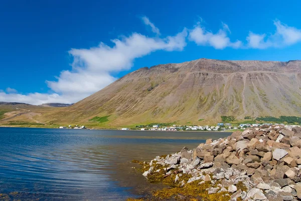 Litoral montanhoso no céu azul ensolarado em Isafjordur, Islândia. Paisagem montanhosa vista do mar. Férias de verão na ilha escandinava. Descubra a natureza selvagem. Wanderlust e conceito de viagem — Fotografia de Stock