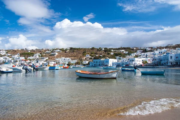 Mykonos, Grécia - 04 de maio de 2010: barcos na água do mar. Praia do mar no céu azul nublado. Casas em paisagem montanhosa com arquitetura mediterrânea. Férias de verão na ilha. Wanderlust e viagens — Fotografia de Stock