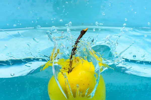 Apfel unter Wasser mit transparenten Blasen und Wassertropfen spritzt. gesunder Lebensstil. Apfelwäsche in reiner, transparenter Flüssigkeit. Früchte fallen ins Wasser, blauer Hintergrund — Stockfoto