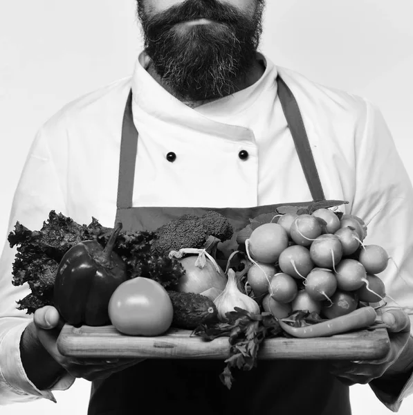 Hälsosam mat. Kocken håller styrelsen med färska grönsaker. Mannen med skägg isolerad på vit bakgrund. Matlagning och vegetarisk kost koncept — Stockfoto