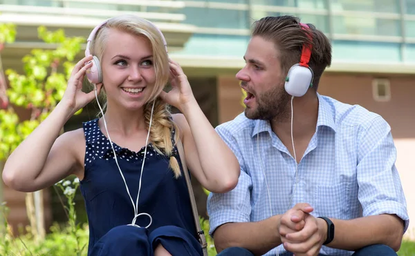 Hombre con mujer disfrutar de la música al aire libre con fondo urbano, desenfocado . — Foto de Stock