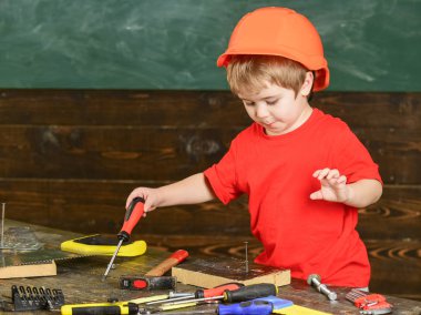 Çocuk Çocuk Tornavida Aracı tutar. Handcrafting ve atölye kavramı. Kask Oluşturucu veya repairer, veya handcrafting şirin çocuk. Yürümeye başlayan çocuk meşgul yüzündeki tornavida ile Atölyesi'nde oynamaktadır.
