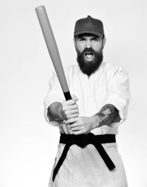 Öfkeli suratlı karateci elinde yeşil beyzbol sopası tutuyor. Beyaz kimonolu sakallı ve beyaz arka planda yeşil şapkalı bir adam. Şiddet ve zorbalık kavramı. Gangster dövüşmeye hazırlanıyor..