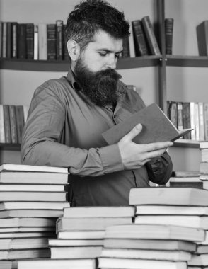 Adam meşgul düşünceli yüz kitap okumak, kitap rafı arka plan üzerinde. Eğitim ve bilim kavramı. Öğretmen veya kitaplığındaki kitap yığınları arasında sakal eğitim ile öğrenci