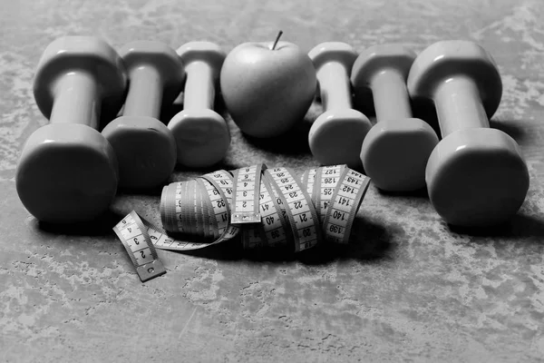 Гантелі придатні. Барбелли, міри стрічки та яблуко, розміщені у візерунку, крупним планом — стокове фото