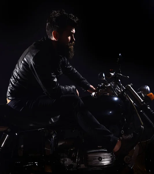 Macho, brutal biker i läder jacka Rider motorcykel nattetid, kopia utrymme. Bikers fritid koncept. Mannen med skägg, biker i skinnjacka sitter på motorcykel i mörker, svart bakgrund — Stockfoto