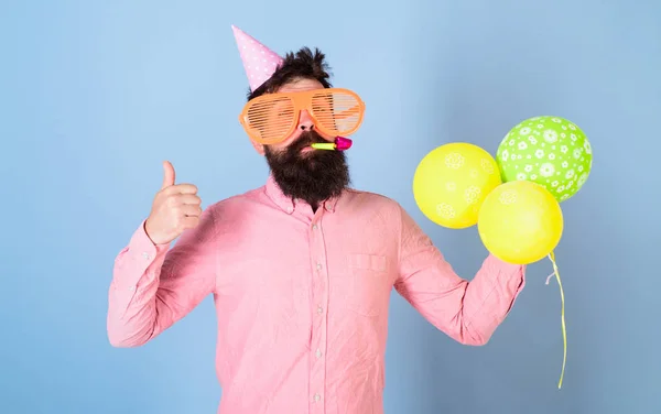 Artista de entretenimento na festa de crianças, celebração internacional do dia das crianças. Homem barbudo com óculos enormes, wistle e balões, conceito divertido. Hipster com barba na moda em camisa rosa no fundo azul — Fotografia de Stock