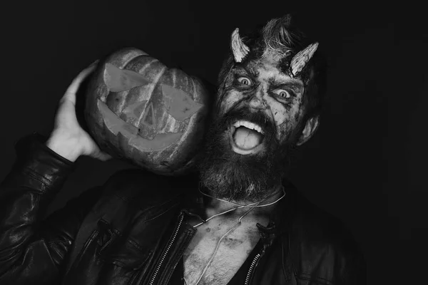 Demonio con cuernos y cara espeluznante sostiene jack o linterna — Foto de Stock