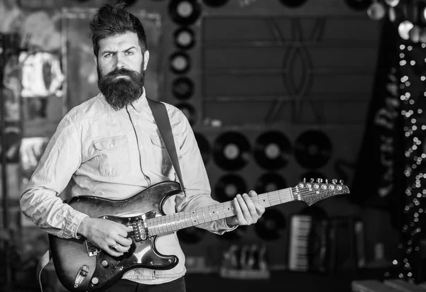 Músico com barba tocar guitarra elétrica. Conceito de música rock. Homem com cara rígida toca guitarra, canta música, toca música. Talentoso músico, solista, cantor tocar guitarra no clube de música em segundo plano — Fotografia de Stock