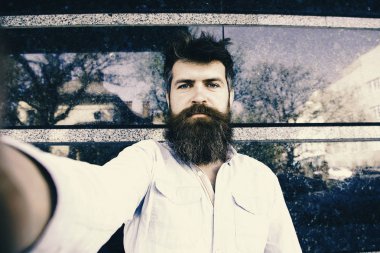 adam selfies yapar. Vlogging kavramı. Selfie fotoğrafta hipster, turist tousled saçlı ve uzun sakal kameraya, seyir.