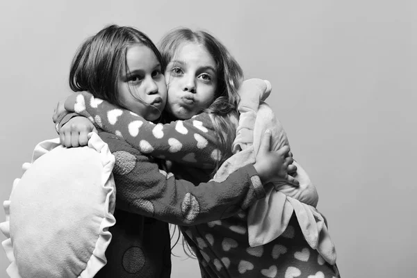 Raparigas felizes. Crianças com caras engraçadas fazem beijos de ar e seguram travesseiros — Fotografia de Stock