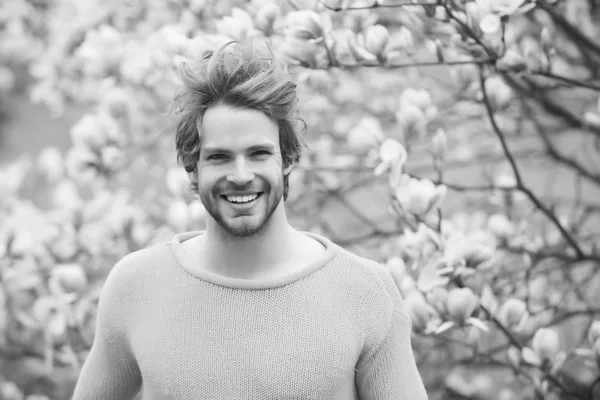 Cara com barba sorrindo em suéter amarelo no fundo floral — Fotografia de Stock