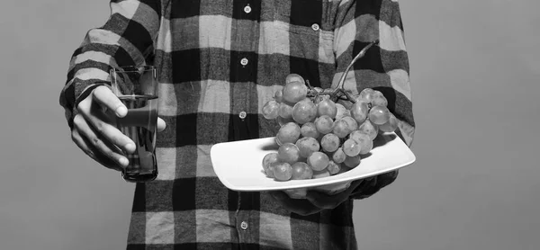 Grape wine. Guy shows harvest. Male hands hold glass of grape juice — Stock Photo, Image