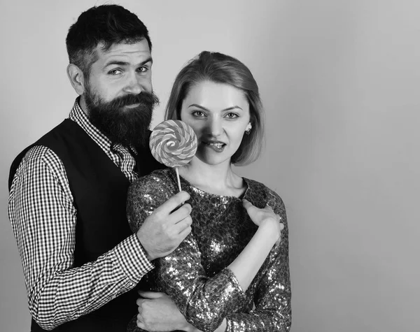 Chica y chico con caras seductoras comer dulces de colores . — Foto de Stock