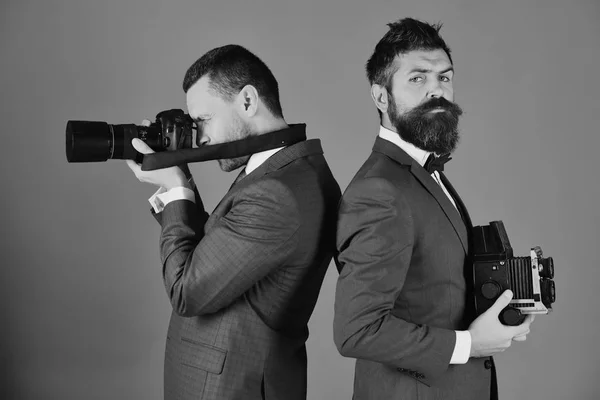 Fotografové pracující. Muži s vousy drží Foto kamery na modrém pozadí — Stock fotografie