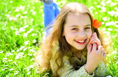 Çimen, grassplot arka plan üzerinde yatan kız. Çocuk çayır çiçeklerle yatarken bahar güneşli günü tadını çıkarın. Mevsimlik Anti kavramı. Kırmızı lale çiçek kız mutlu yüz tutan, aroma zevk