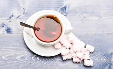 Çay molası kavramı. Daldırma galvaniz çay poşeti ve marshmallow ile çay kupa. İçki bira Kupası, üstten görünüm işlemidir. Siyah çay demlendi, kaşık ve hatmi ahşap zemin üzerine yığını kupa dolu