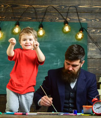 Neşeli çocuk ve resim, çizim öğretmen. Sanat ders kavramı. Sakallı öğretmeni, sınıfta, kara tahta arka plan çizmek için küçük oğlu baba öğretir. Yetenekli sanatçı oğlumla vakit geçirmek