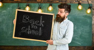 Gözlük öğretmen okul için başlıklı yazı tahtası tutar. Eğitim ve eğitim kavramı. Sakal ve bıyık sakin yüz memnuniyetle öğrencilerin, kara tahta arka plan ile adam