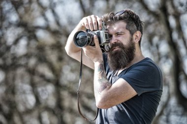 Güneşli günde fotoğrafta sakallı adam. Fotoğrafçı kavramı. Fotoğraf çekimi ile meşgul uzun sakallı adam. Adam sakal ve bıyık konsantre yüzündeki defocused arka plan, dallarda