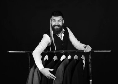 Siyah arka plandaki ceketlerin yanında neşeli yüzlü bir iş adamı..