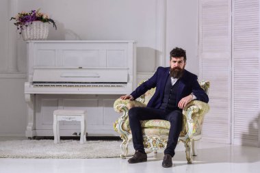 Maço çekici ve zarif eski moda koltukta oturan ciddi, düşünceli yüzünde. Servet ve zenginlik kavram. Sakal ve bıyık Klasik takım, şık şık kıyafet giyen adamla