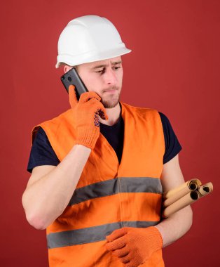 Mühendis, mimar, Oluşturucu meşgul yüzündeki konuşuyor Smartphone cep telefonu ile ayrı tutma planları yaparken. Mimar kavramı. Dostum, foreman kask içinde inşaat telefon, kırmızı zemin üzerine denetler