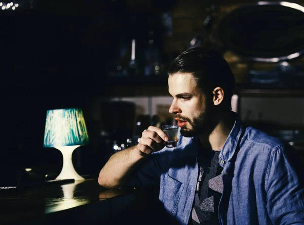 Mężczyzna z brodą pije alkohol w barze na niewyraźnym tle. — Zdjęcie stockowe