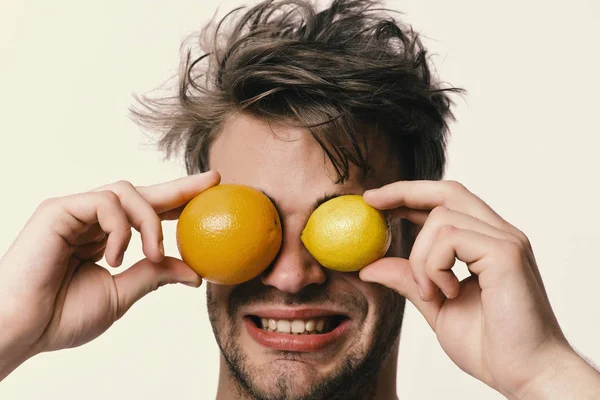 Hombre con naranja y limón en vez de ojos en las manos — Foto de Stock