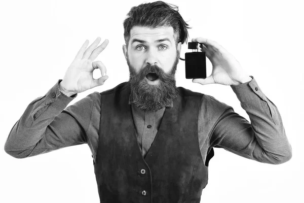 Бородатый мужчина держит духи с удивленным лицом — стоковое фото