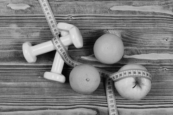 Ginásio e conceito de saúde, halteres peso com fita métrica, frutas — Fotografia de Stock
