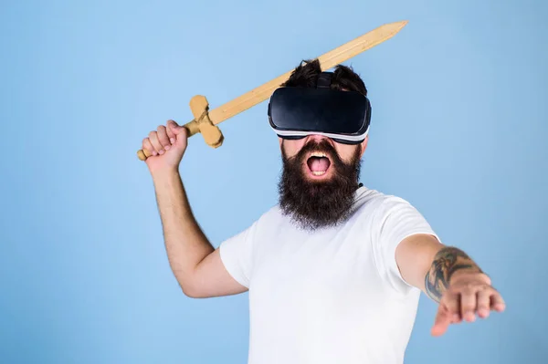 Hipster krzyku twarz cieszyć się gry w wirtualnej rzeczywistości. Koncepcja gamer VR. Człowiek z brodą w okulary Vr, jasnoniebieskie tło. Facet z głowy na wyświetlaczu zamontowanym i miecz gry bijatyka w Vr — Zdjęcie stockowe
