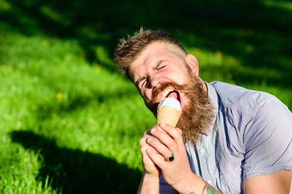 Homem barbudo segura cone de sorvete como microfone. Conceito de cantor. Um homem de barba comprida a cantar. Homem com barba e bigode no rosto gritando desfrutar de sorvete, grama no fundo, desfocado — Fotografia de Stock