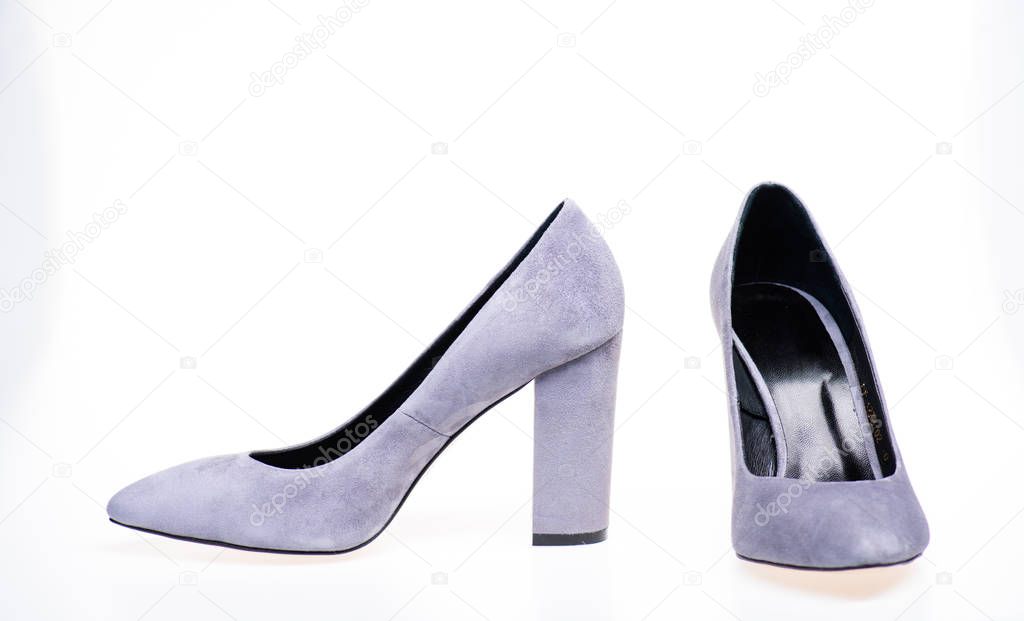 Pair of fashionable high heeled shoes. Shoes made out of grey suede on white background, isolated, copy space. Footwear for women with thick high heels. Fashionable shoes concept