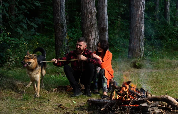 Paar mit Schäferhund am Lagerfeuer, — Stockfoto