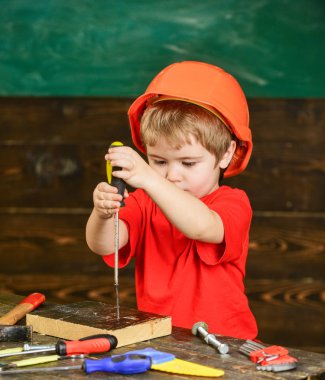 Çocuk Çocuk Tornavida Aracı tutar. Yürümeye başlayan çocuk meşgul yüzündeki tornavida ile Atölyesi'nde oynamaktadır. Kask Oluşturucu veya repairer, veya handcrafting şirin çocuk. Handcrafting ve atölye kavramı