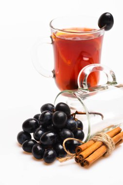 Mevsimlik içecek konsepti. Gözlük mulled şarap ile veya sıcak içecek üzüm ve beyaz zemin üzerine tarçın ile kapatın. Üzüm ve tarçın ile mulled şarap cam