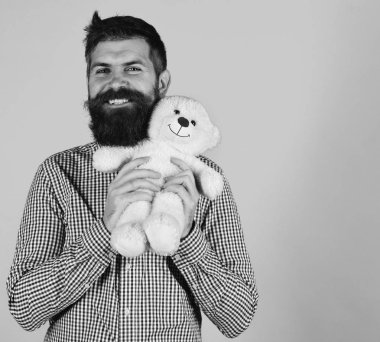 Oyuncak Dükkanı. Adam oyuncak ayı mavi arka plan üzerinde tutar. Sakallı