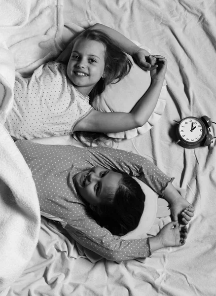 happy girls. Schoolgirls in pink pajamas wallow on colorful pillows, top view