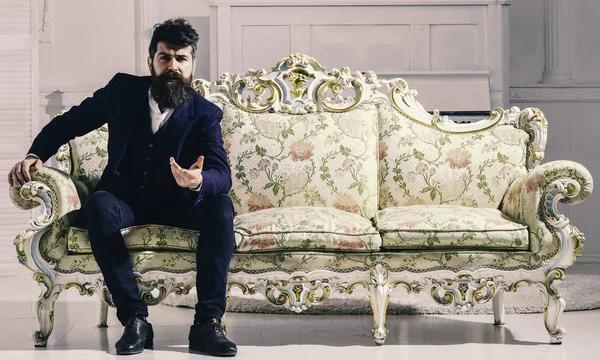 Rich man. Fashion and style concept. Man with beard and mustache wearing fashionable classic suit, sits on old fashioned couch or sofa. — Stock Photo, Image