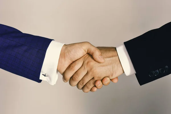 Handshake on light grey background. Businessmen wear smart suits