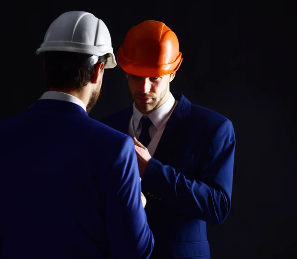 Compañeros de trabajo en trajes formales y cascos de construcción . — Foto de Stock