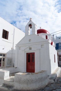 Mykonos, Yunanistan'ın bina Kilisesi. Şapel çan kulesi ve kırmızı kubbe ile. Bulutlu gökyüzü beyaz Kilise mimarisi. Yaz tatili bir Akdeniz Adası, yolculuk tutkusu. Din ve kült kavramı
