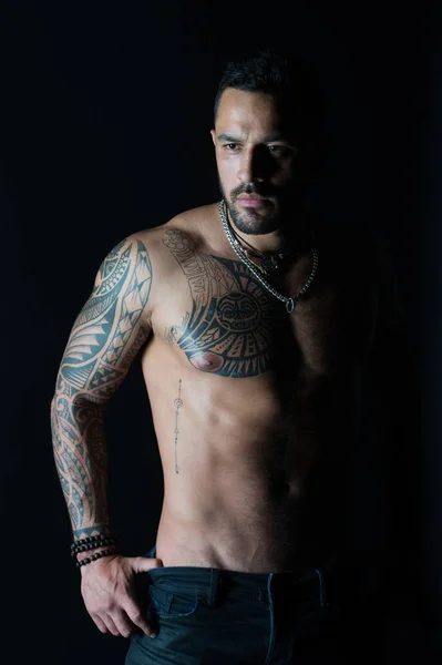 Man with tattooed arm and chest. Bearded man with strong torso. Tattoo model with sexy belly. Sportsman or athlete in fashion jeans. Bodycare or fitness and sport — Stock Photo, Image