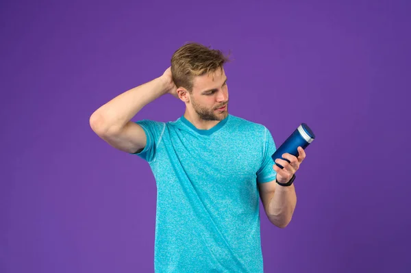 Man on confident face touching his hair, violet background. Guy with bristle holds bottle with shampoo, copy space. Man enjoy freshness after washing hair with shampoo. Hair care and shampoo concept — Stock Photo, Image