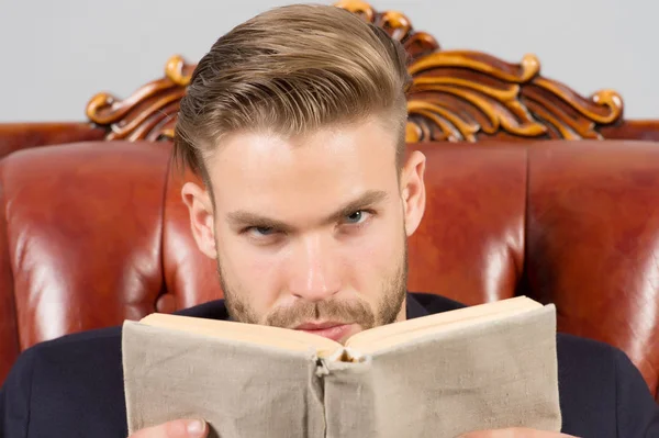 Katı yüz okuma, ders çalışma, kendini geliştirme. İş eğitimi konsepti. Tüylü adam başarılı ve zeki bir girişimci. İş adamı resmi takımı deri koltuğa oturur, gri arka plan