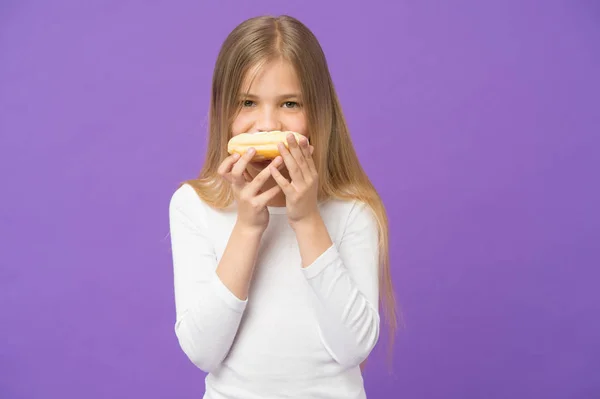 Έχοντας σνακ. Παιδί τρώει ντόνατ σε μοβ φόντο. Κοριτσάκι με τζάμια δαχτυλίδι ντόνατ σε μοβ φόντο. Παιδί με πρόχειρο φαγητό. Τροφή για σνακ και επιδόρπιο. Παιδική ηλικία και την φροντίδα των παιδιών, αντίγραφο χώρου — Φωτογραφία Αρχείου